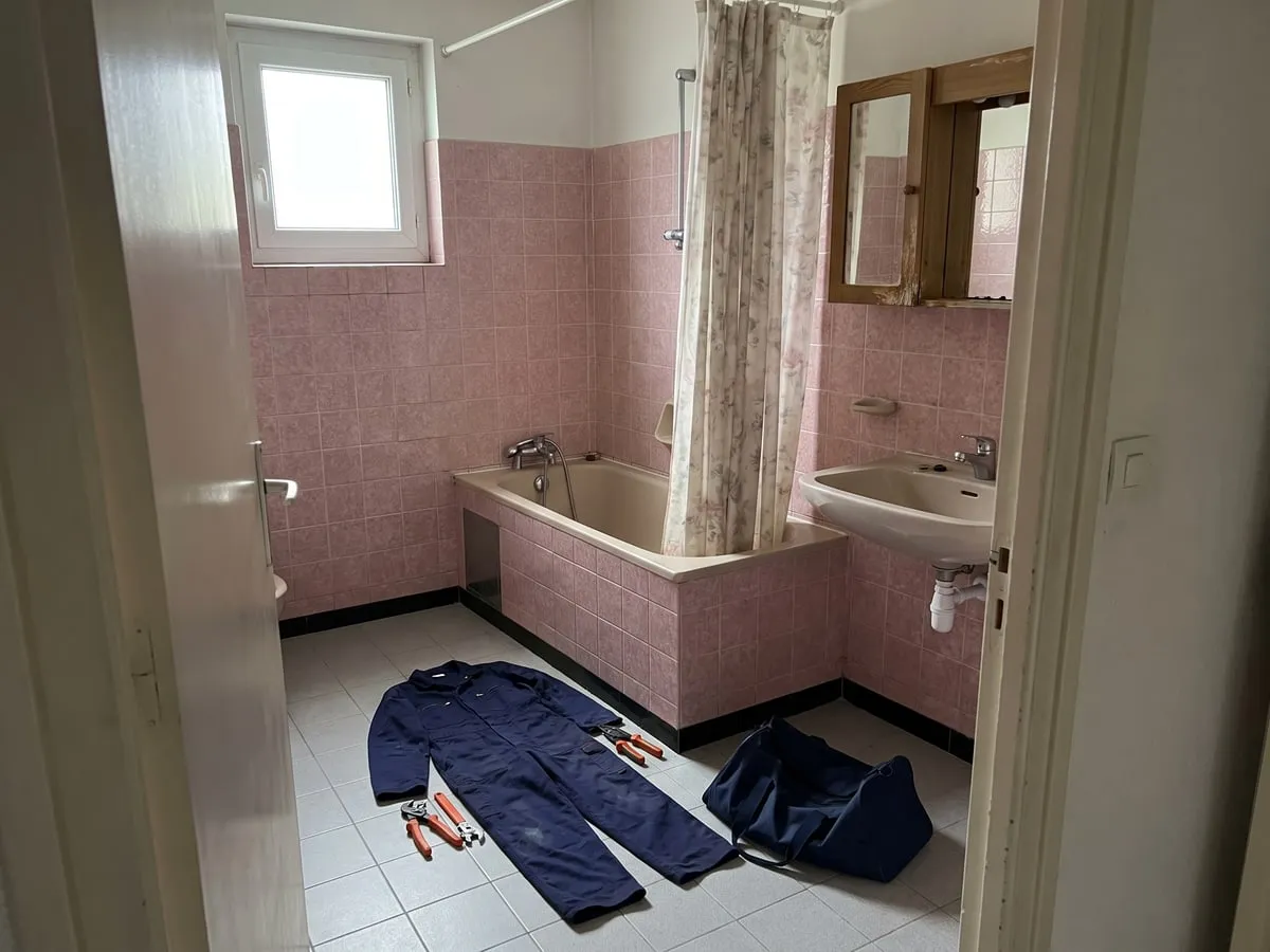 Avant : une salle de bain des années 90 avec baignoire, carrelage rose et joints noircis