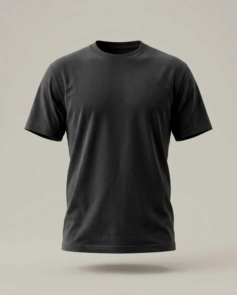 Le T-shirt Essentiel noir, de face, comme porté, sur un fond de pierre claire