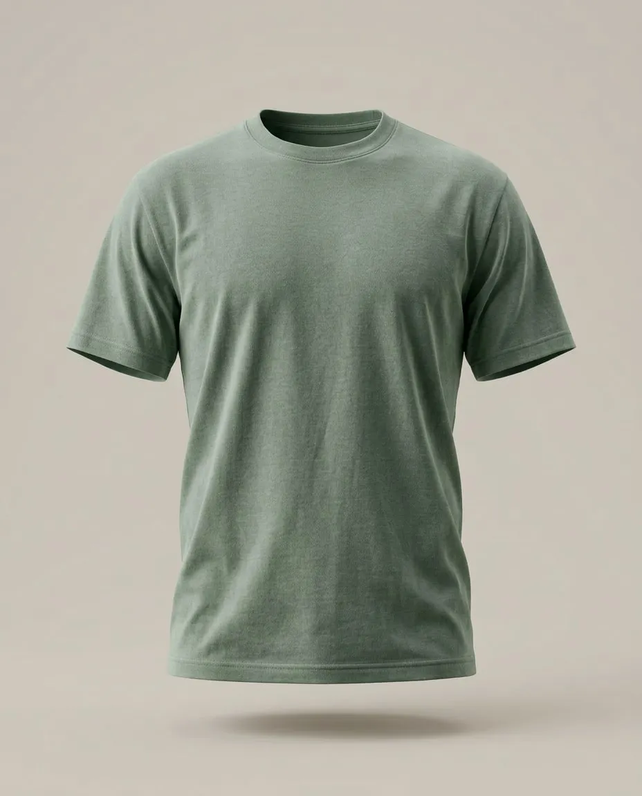 Le T-shirt Essentiel vert sauge, de face, comme porté, sur un fond de pierre claire